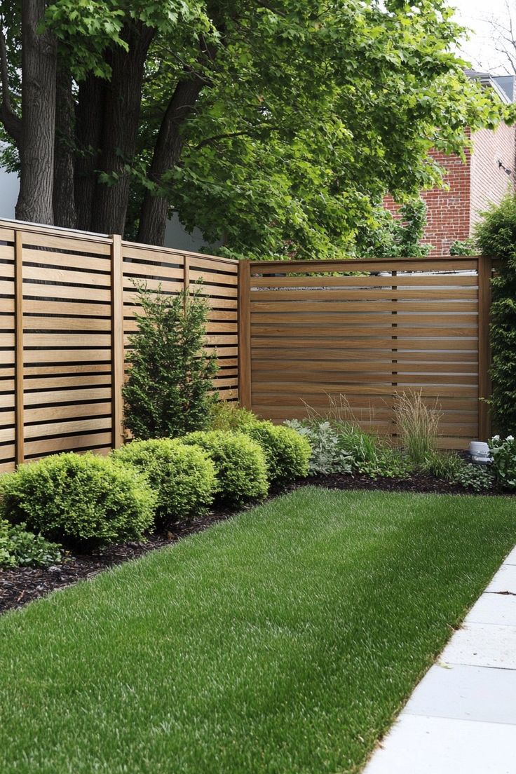 Horizontal slat wood fence with shrubs and fresh lawn