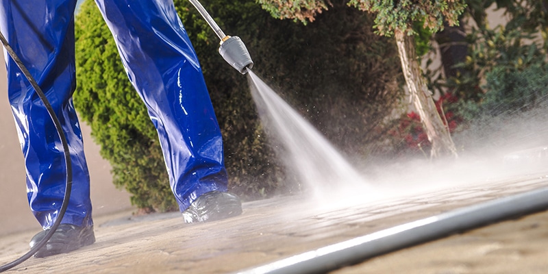 Worker pressure washing a paved patio