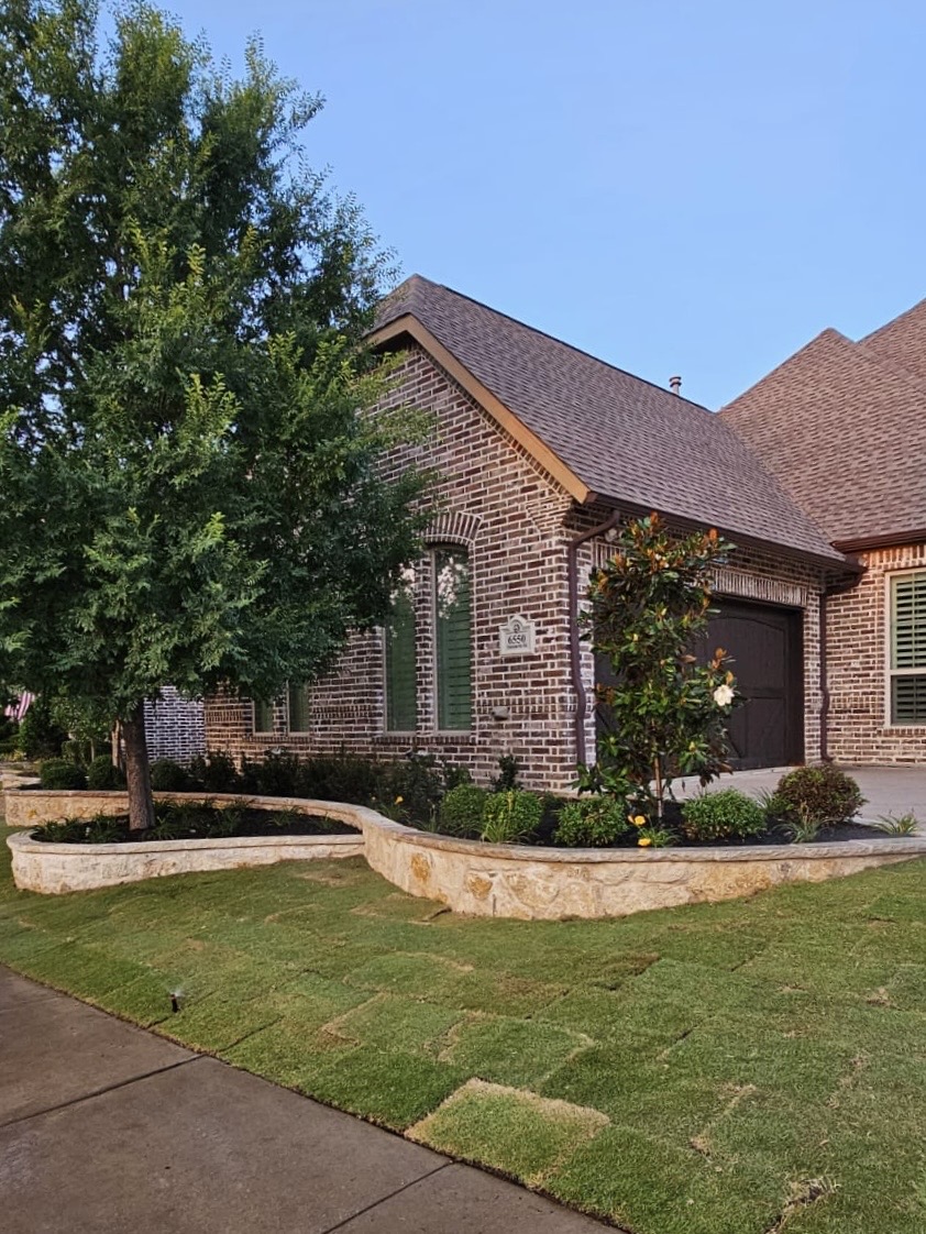 Curved natural stone border and new sod in front of a brick home